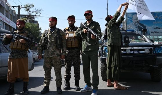Taliban fighters stand guard along a road in Kabul on Thursday.