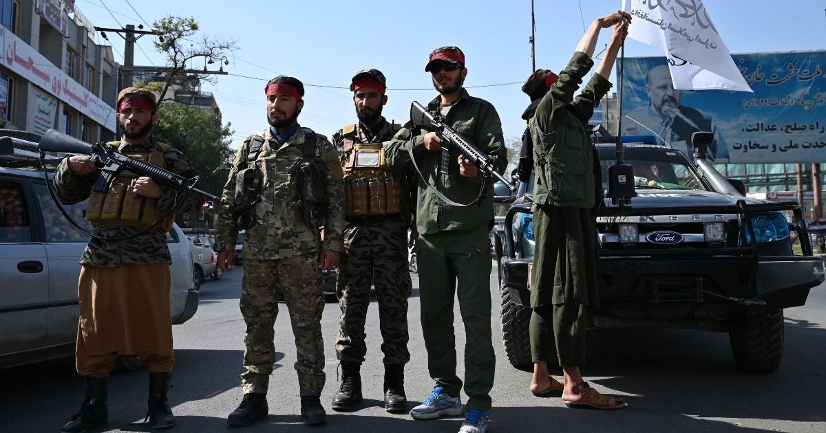 Taliban fighters stand guard along a road in Kabul on Thursday.
