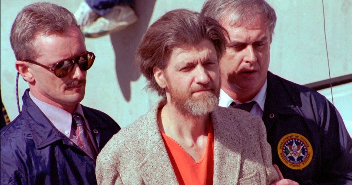 Theodore John Kaczynski, nicknamed the Unabomber, is flanked by federal agents as he is led to a car from the federal courthouse in Helena, Montana, on April 4, 1996.