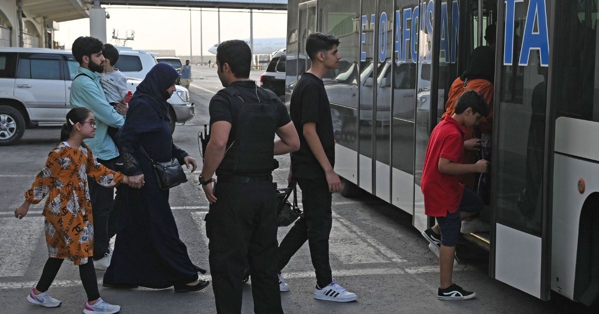 A group of Afghans are seen boarding a shuttle bus at the Kabul airport on Friday.