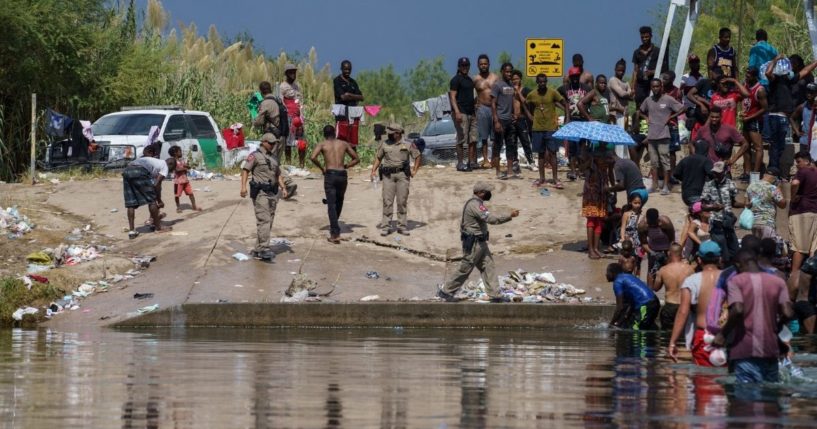Texas state troopers deal with a large group of illegal immigrants, many from Haiti, along the Rio Grande next near the Del Rio-Acuna Port of Entry in Del Rio, Texas, on Saturday.