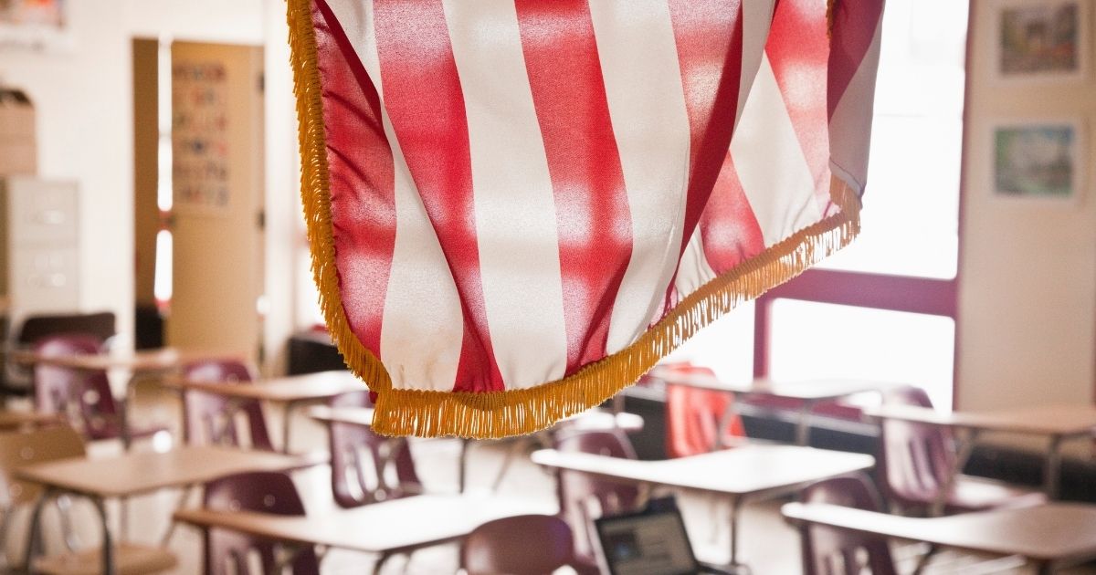 A stock photo shows the American flag hanging in a classroom at a school.