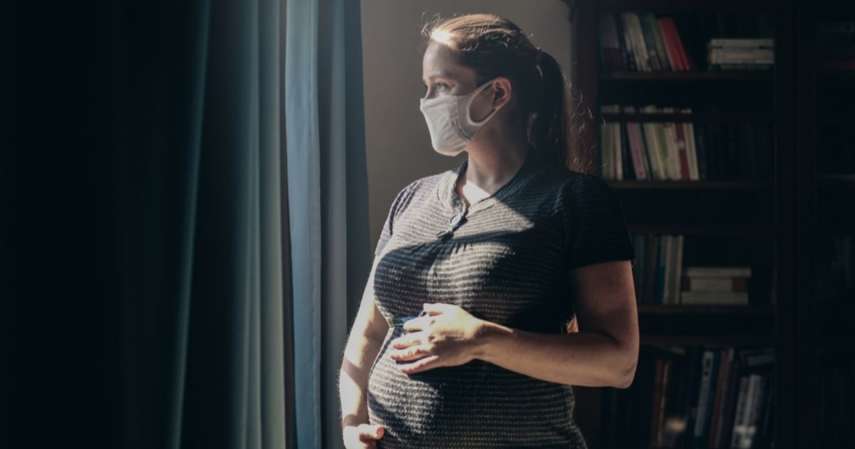 A pregnant woman wearing a mask is seen in this stock image.