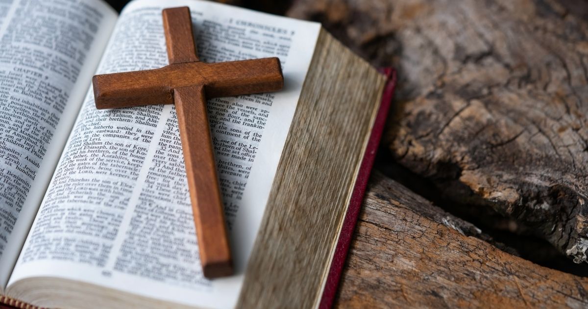 A stock photo shows a wooden cross resting on top of the Holy Bible.