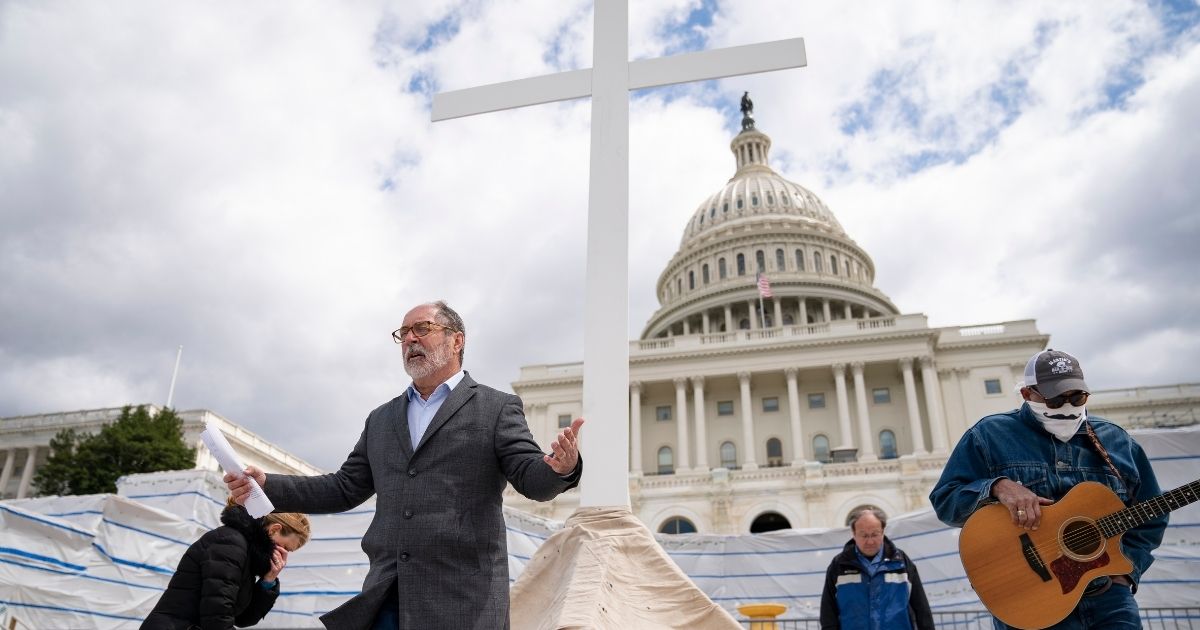 The Rev. Patrick Mahoney, director of the Christian Defense Coalition, kneels in prayer as he livestreams a Good Friday service on the grounds of the U.S. Capitol on April 10, 2020, in Washington.