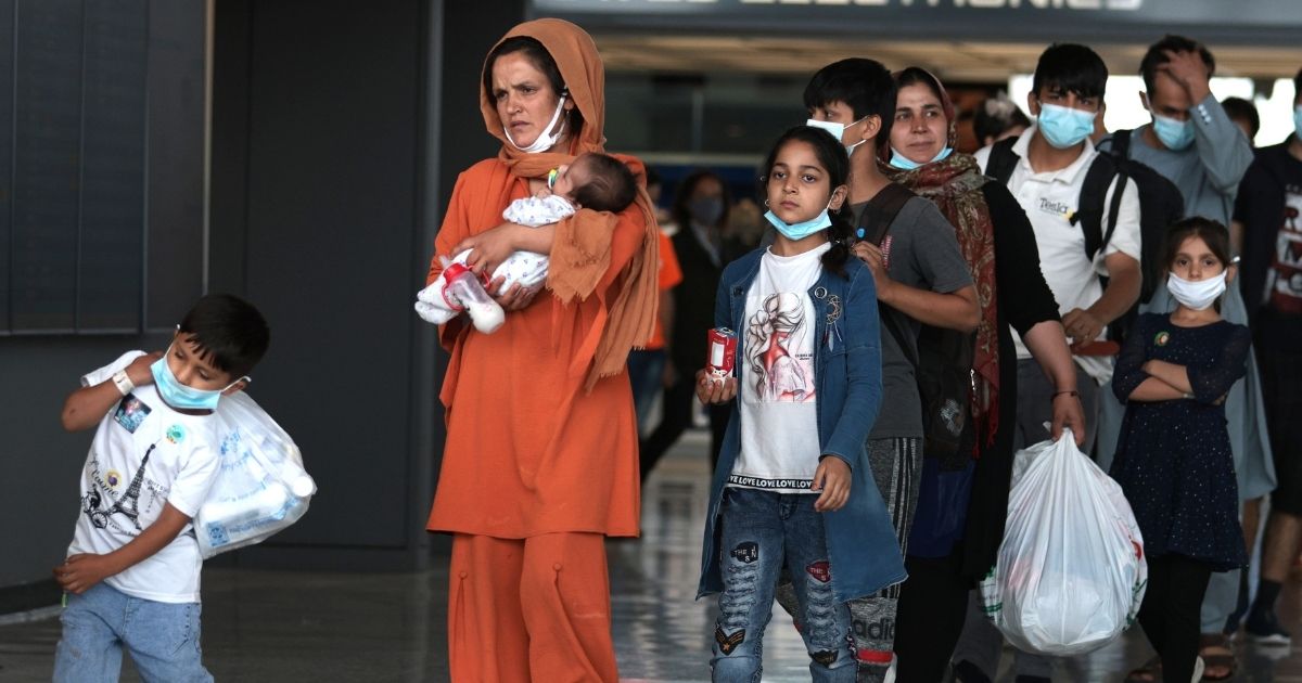 Refugees walk through the departure terminal to a bus at Dulles International Airport after being evacuated from Kabul following the Taliban takeover of Afghanistan on Aug. 31, in Dulles, Virginia.