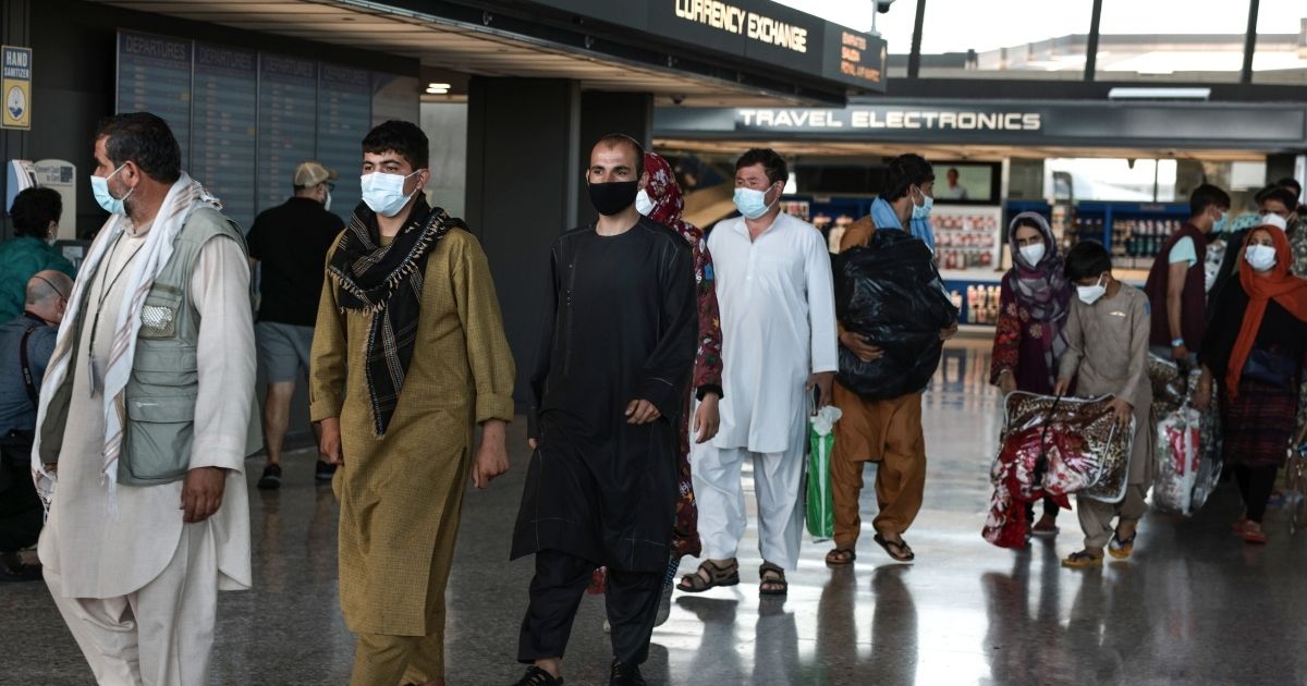 People evacuated from Afghanistan are led through the arrival terminal at the Dulles International Airport to board a bus that will take them to a refugee processing center on Aug. 25, in Dulles, Virginia.