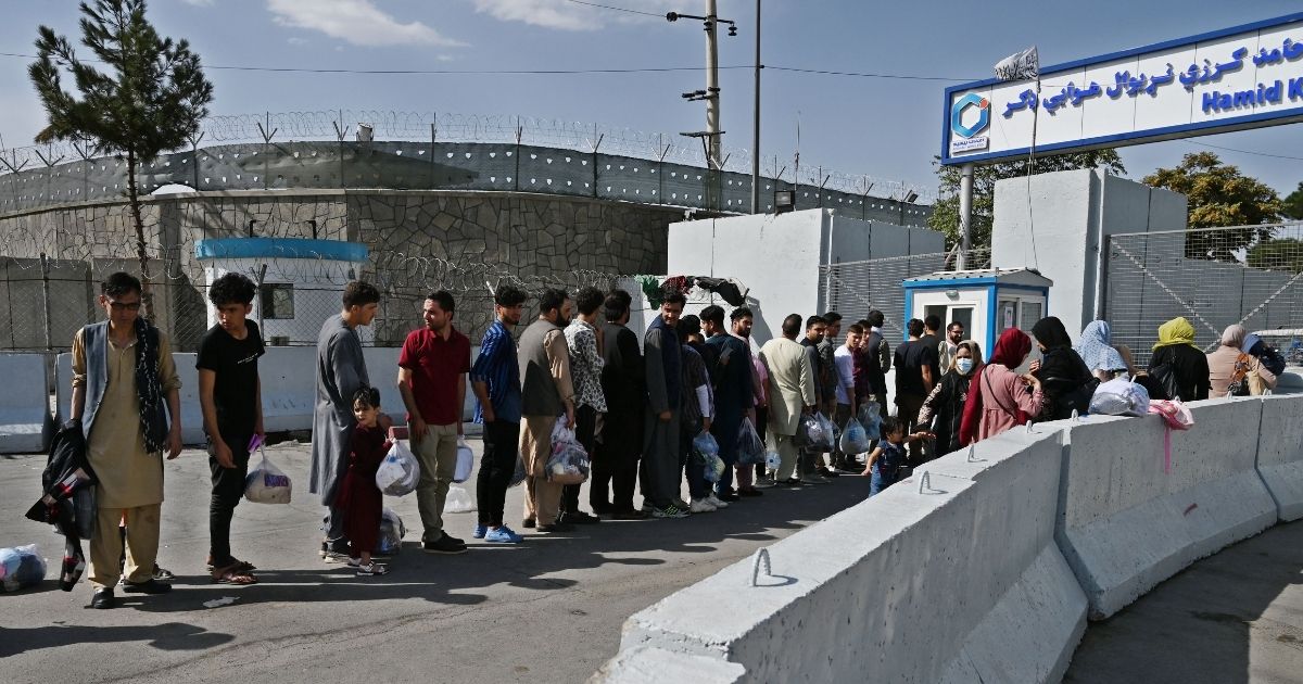 Afghans, hoping to leave Afghanistan, queue at the main entrance gate of Kabul airport in Kabul on Aug. 28.