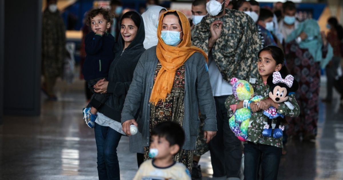 A family of people evacuated from Afghanistan are led through the arrival terminal at the Dulles International Airport to board a bus that will take them to a refugee processing center on Aug. 25, in Dulles, Virginia.