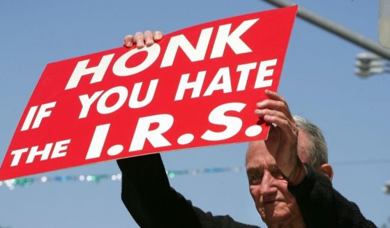 J.D. Montgomery holds a sign on the street outside of the James C. Corman Federal Building in Van Nuys, California, encouraging motorists to express their anger at the Internal Revenue Service on April 17, 2006, the final day to file 2005 income taxes.
