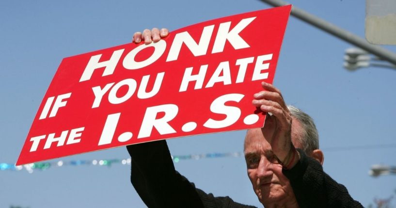 J.D. Montgomery holds a sign on the street outside of the James C. Corman Federal Building in Van Nuys, California, encouraging motorists to express their anger at the Internal Revenue Service on April 17, 2006, the final day to file 2005 income taxes.