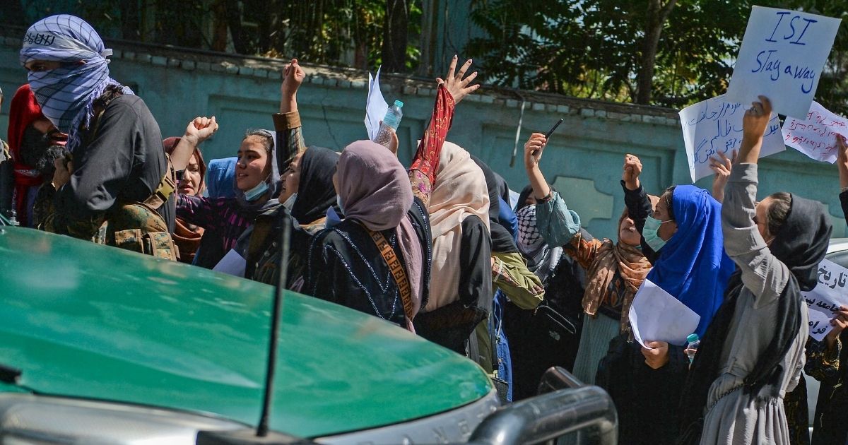 Afghan women shout slogans next to a Taliban fighter during an anti-Pakistan demonstration near the Pakistan embassy in Kabul on Sept. 7, 2021.