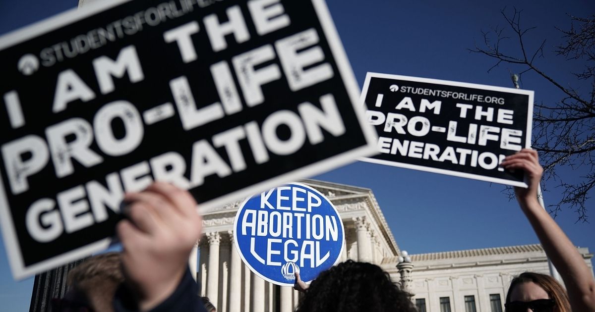 Pro-life activists try to block the sign of a pro-choice activist during the 2018 March for Life on Jan. 19, 2018, in Washington, D.C.