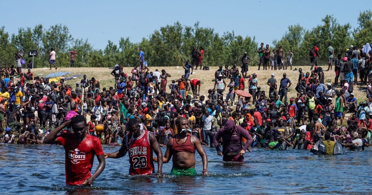 Haitian migrants, part of a group of over 10,000 people staying in an encampment on the US side of the border, cross the Rio Grande river to get food and water in Mexico in a Sept. 19 photo.