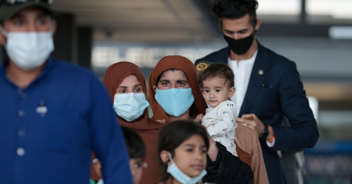 Refugees walk through the departure terminal to a bus at Dulles International Airport after being evacuated from Kabul following the Taliban takeover of Afghanistan on Aug. 31, in Dulles, Virginia.