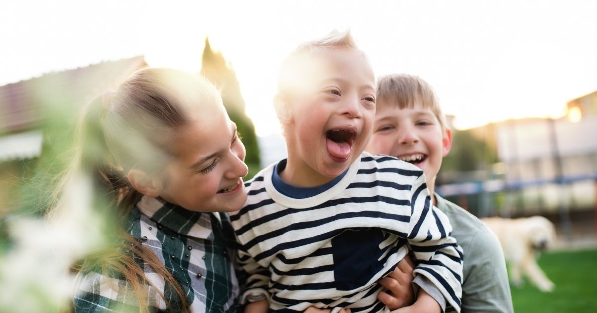 A boy and girl play with a child who has Down syndrome in this stock image.