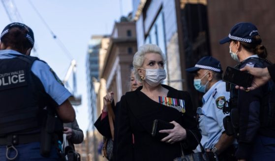 A protester stands near several police officers while speaking to the media during an anti-lockdown protest on Monday in Sydney.