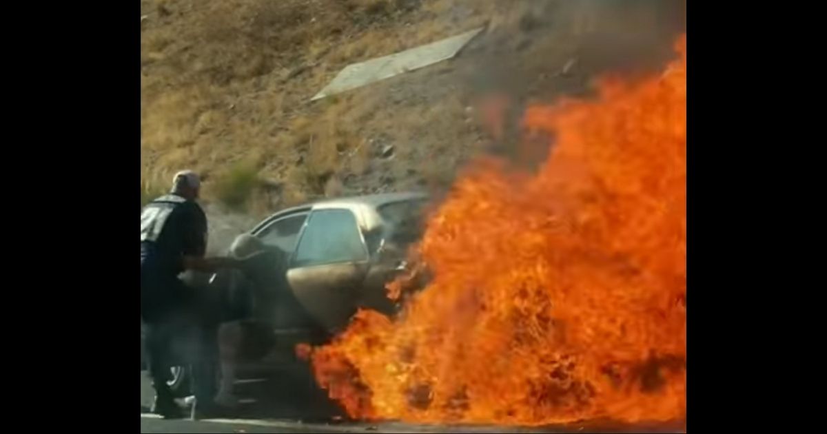 A good Samaritan pulls an elderly man from his burning car near San Digeo on Monday.