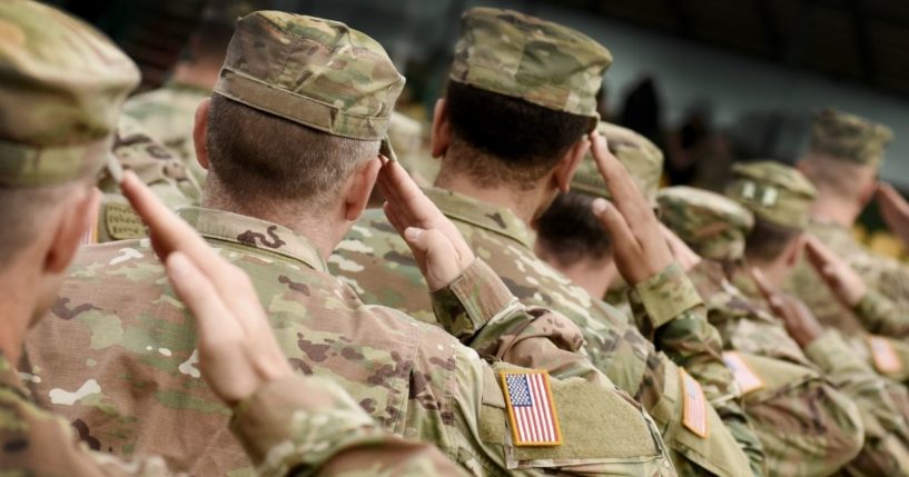 Soldiers salute in this stock image.