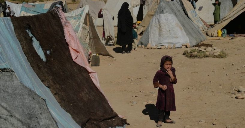 An Afghan girl stands next to tents at a temporary camp near a highway between Herat and Badghis on October 14, 2021. With winter coming on and most of the country plunged into abject poverty, some Afghan parents have resorted to the unthinkable: selling a child to survive.