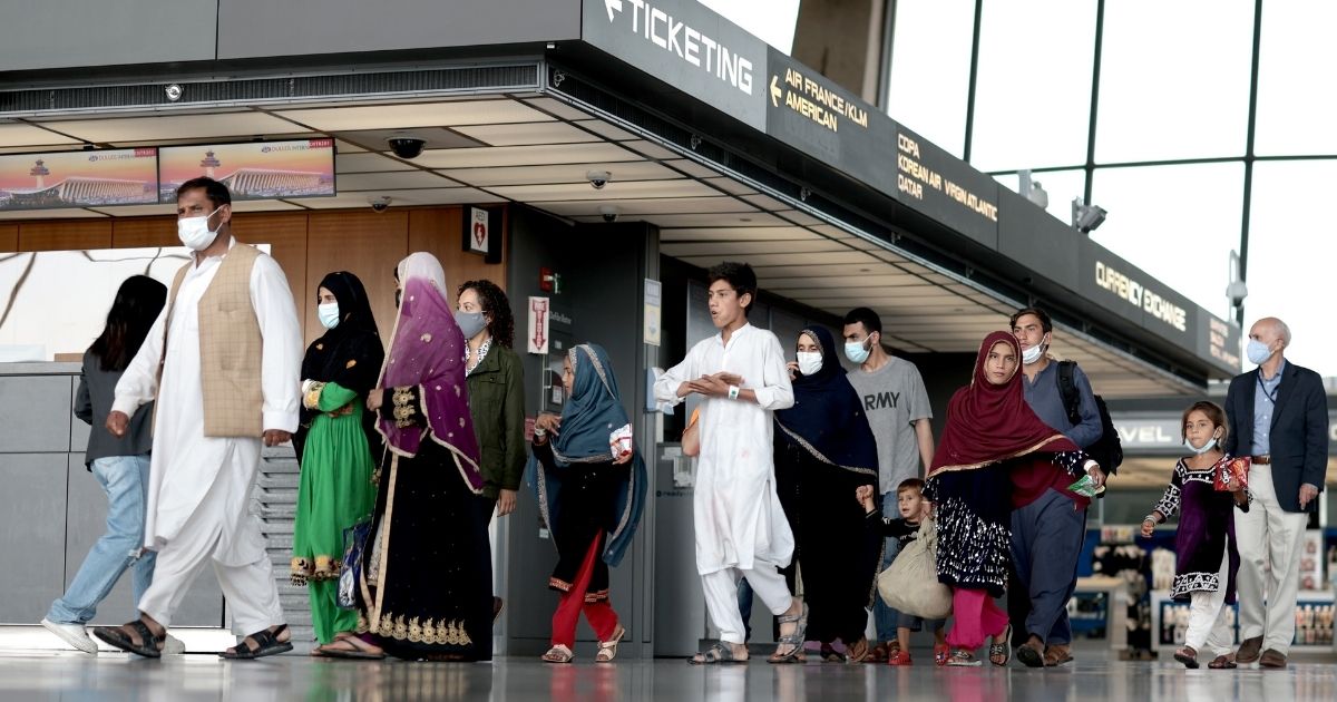 Afghan refugees walk through the departure terminal to a bus at Dulles International Airport in Virginia on Aug. 31 after being evacuated from Kabul following the Taliban takeover of Afghanistan.