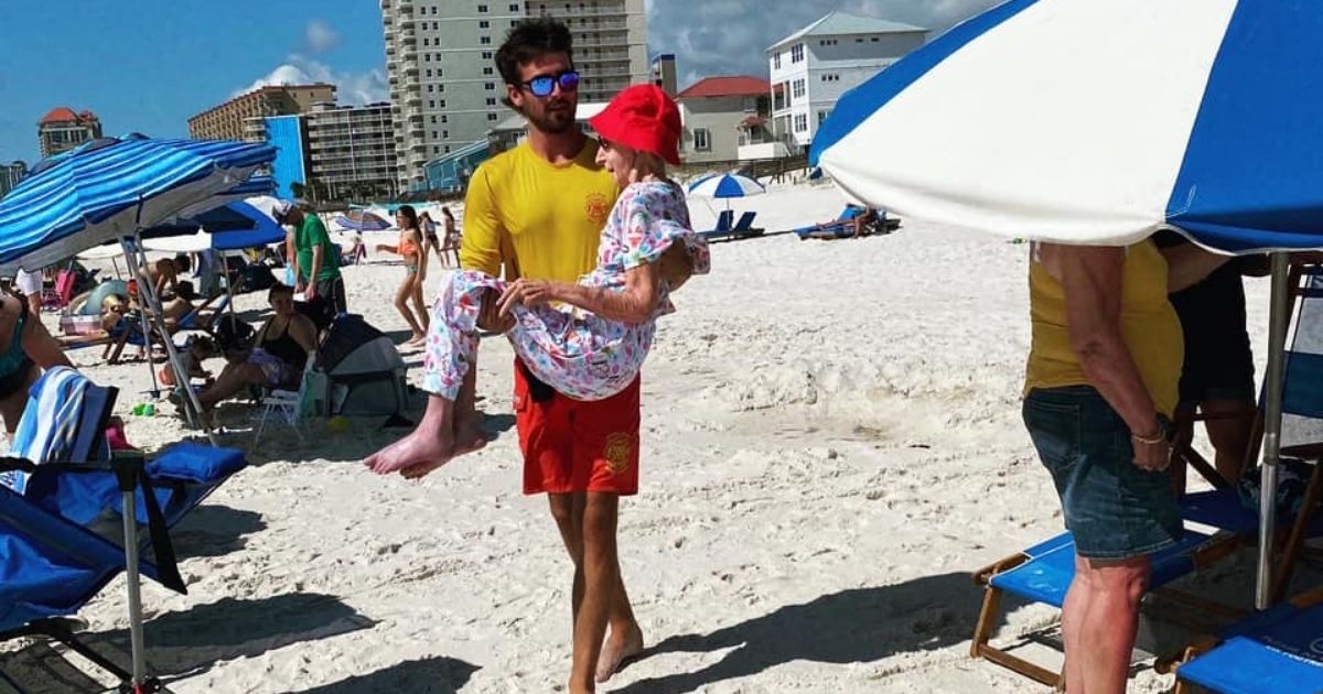 Lifeguard Shane Martin helps 95-year-old Dottie Schneider across the beach in Orange Beach, Alabama.