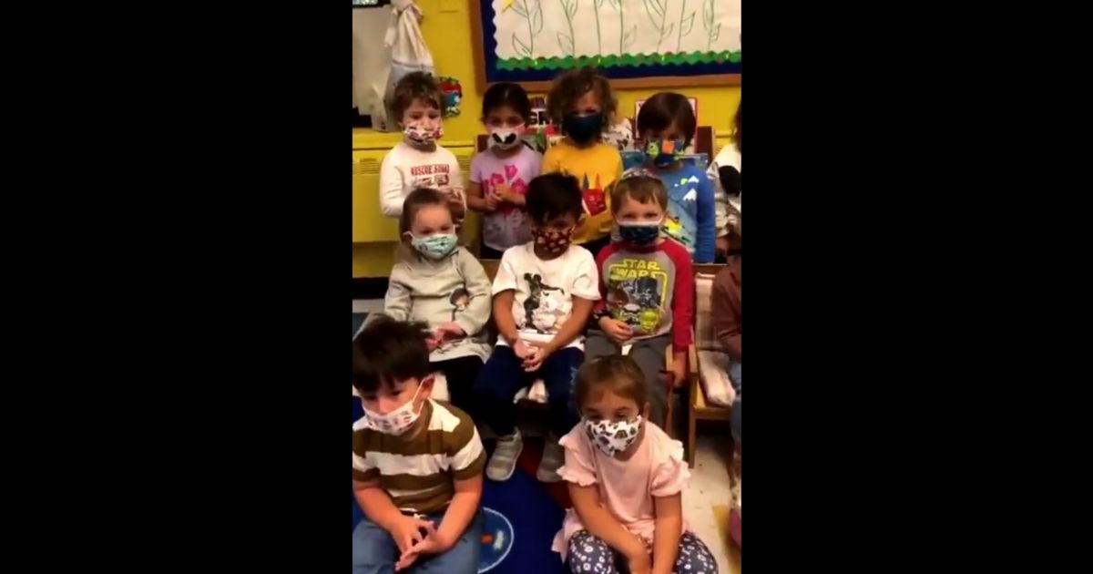 Young children are seen listening to a song about the importance of wearing masks.