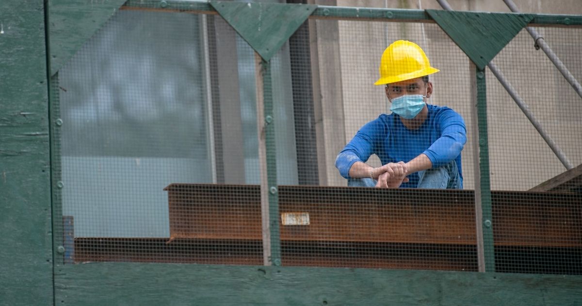 A construction worker wearing a mask and hard hat sits on top of scaffolding amid the coronavirus pandemic on May 22, 2020, in New York City.