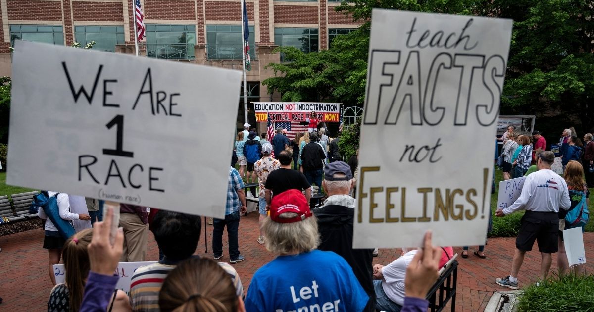 People hold up signs during a rally against critical race theory being taught in schools at the Loudoun County Government Center in Leesburg, Virginia, on June 12.