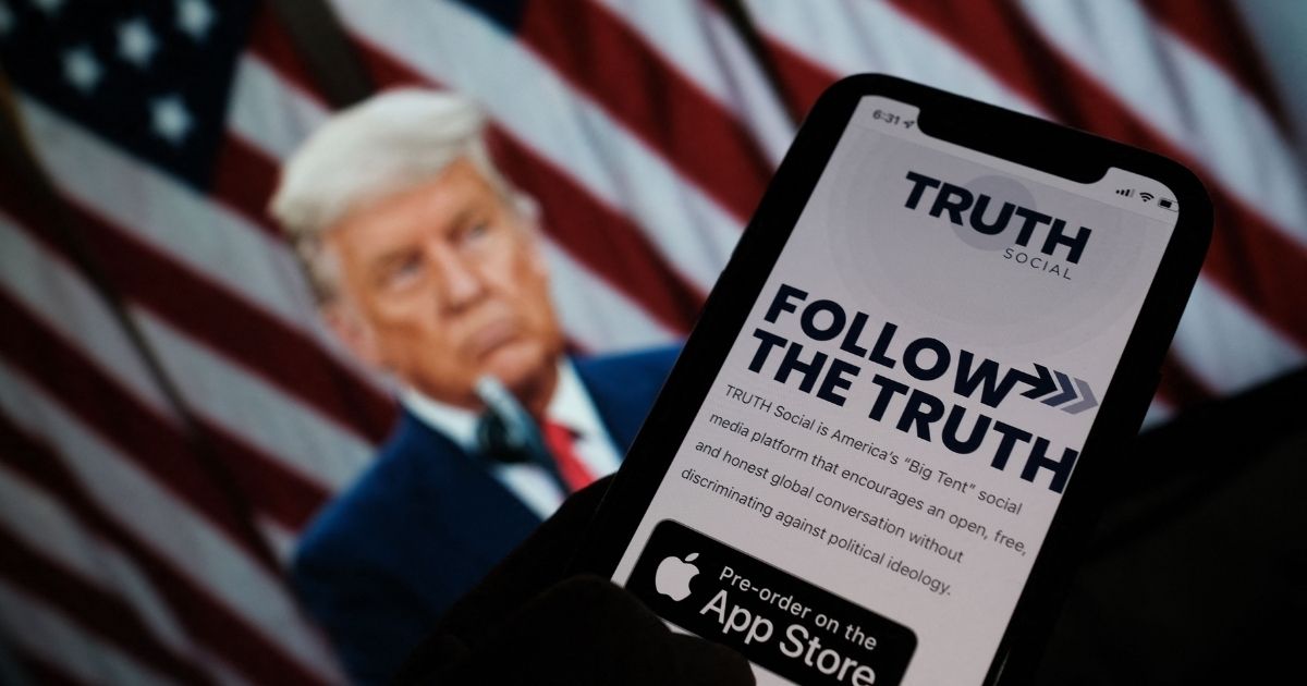 A person checks the app store on a smartphone with a photo of former President Donald Trump in the background in Los Angeles on Wednesday.
