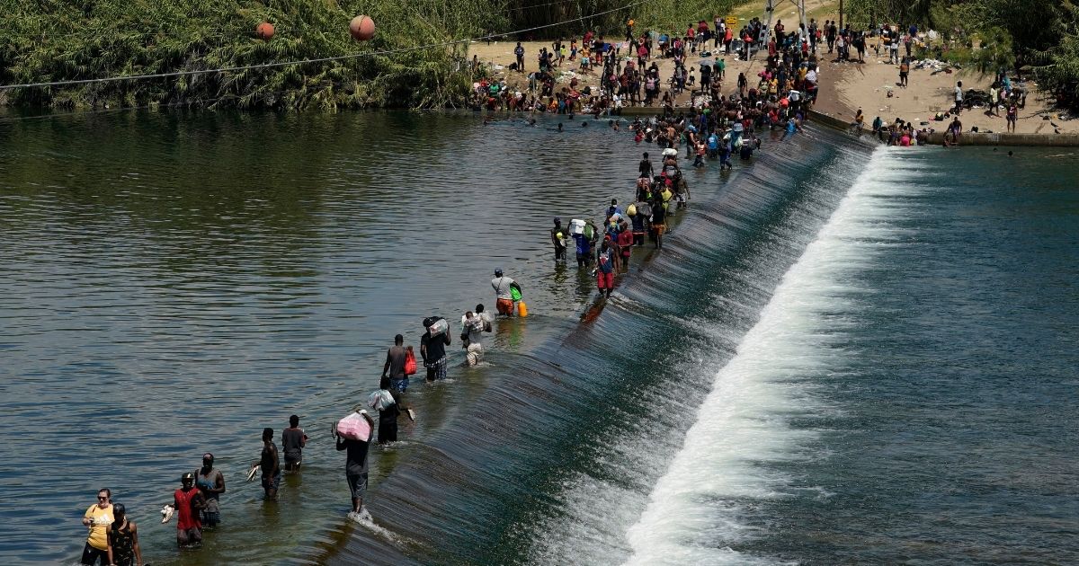 Haitian migrants cross into the United States in large numbers, using a dam in the river near Del Rio, Texas on Sept. 18.