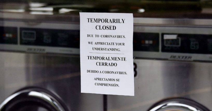 A laundromat window displays a sign explaining its status as temporarily closed as more businesses make the decision to reopen amid the coronavirus pandemic on May 18, 2020, in Arlington, Virginia.