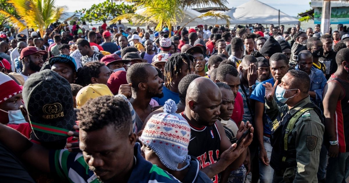 Haitian immigrants wait after Colombian police temporarily closed a ferry boat ticket office because of crowd control issues in Necocli, Colombia, on Monday.