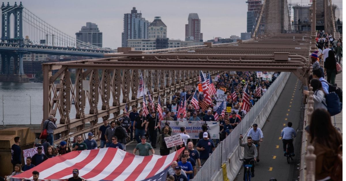Thousands of New York City municipal workers marched across Brooklyn Bridge during a Monday protest against the city's COVID-19 vaccine mandate.