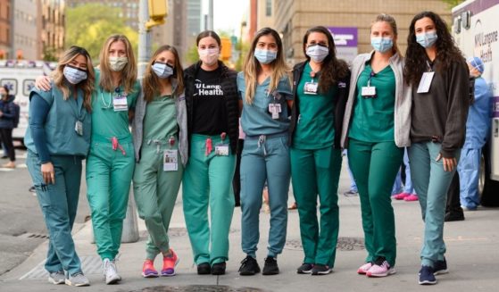 Medical workers stand outside NYU Langone Health hospital in New York City as people applaud to show their gratitude to medical staff and essential workers during the coronavirus pandemic on May 12, 2020.