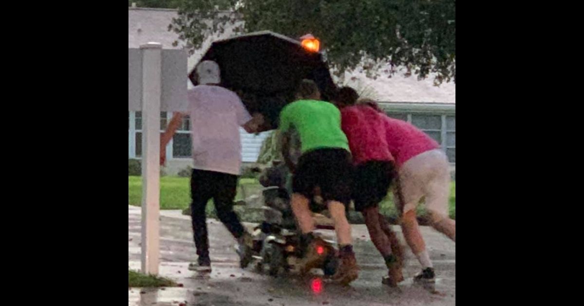Four good Samaritans push an elderly woman in a scooter
