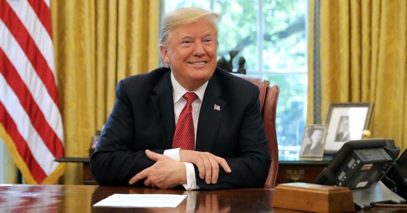 Then-President Donald Trump talks to reporters while hosting workers and members of his Cabinet for a meeting in the Oval Office at the White House on Oct. 17, 2018.