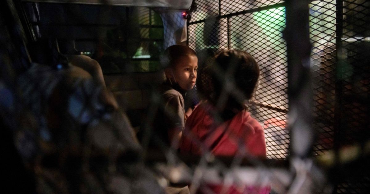 Two unaccompanied children who illegally crossed the Rio Grande from Mexico stand at a makeshift processing checkpoint before being detained by Border Patrol agents in Roma, Texas, on March 27.