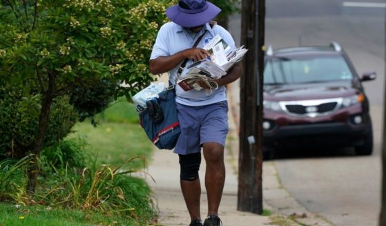 A U.S. Postal Service carrier walks his route in Mount Lebanon, Pennsylvania, on Sept. 21, 2021.