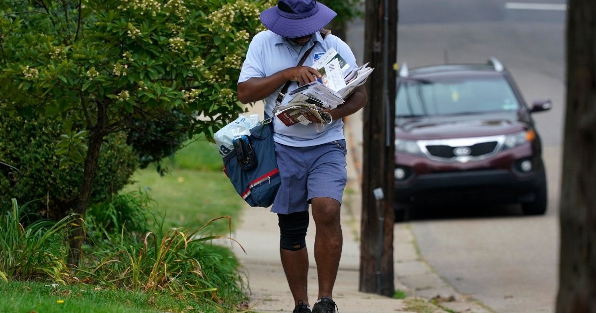 A U.S. Postal Service carrier walks his route in Mount Lebanon, Pennsylvania, on Sept. 21, 2021.