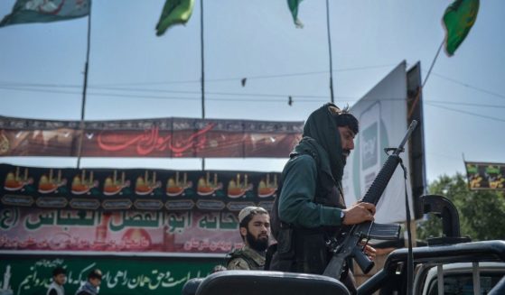 A Taliban fighter climbs onto a vehicle in the same location where the Shiite Muslims distribute sherbet on a road in Kabul, Afghanistan, Aug. 19.