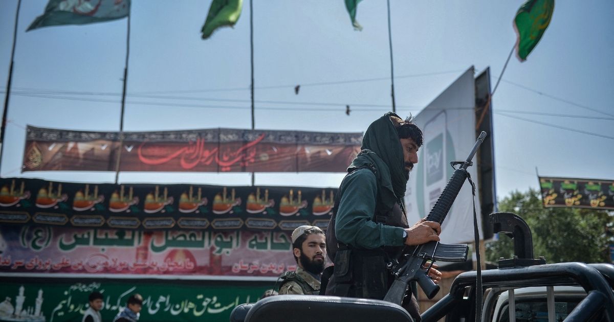 A Taliban fighter climbs onto a vehicle in the same location where the Shiite Muslims distribute sherbet on a road in Kabul, Afghanistan, Aug. 19.