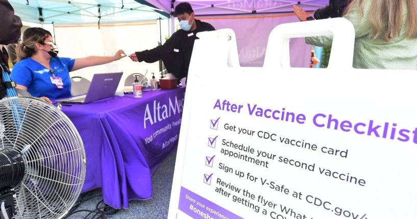 A nurse hands out a vaccine card to people receiving the COVID-19 vaccine in Los Angeles on Aug. 21.