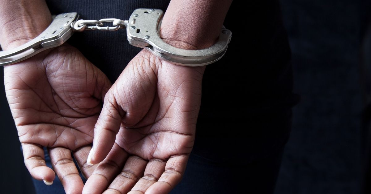A stock photo shows a woman in handcuffs.