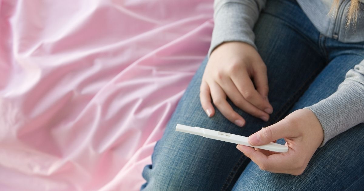 A stock photo shows a teenage girl holding a pregnancy test.