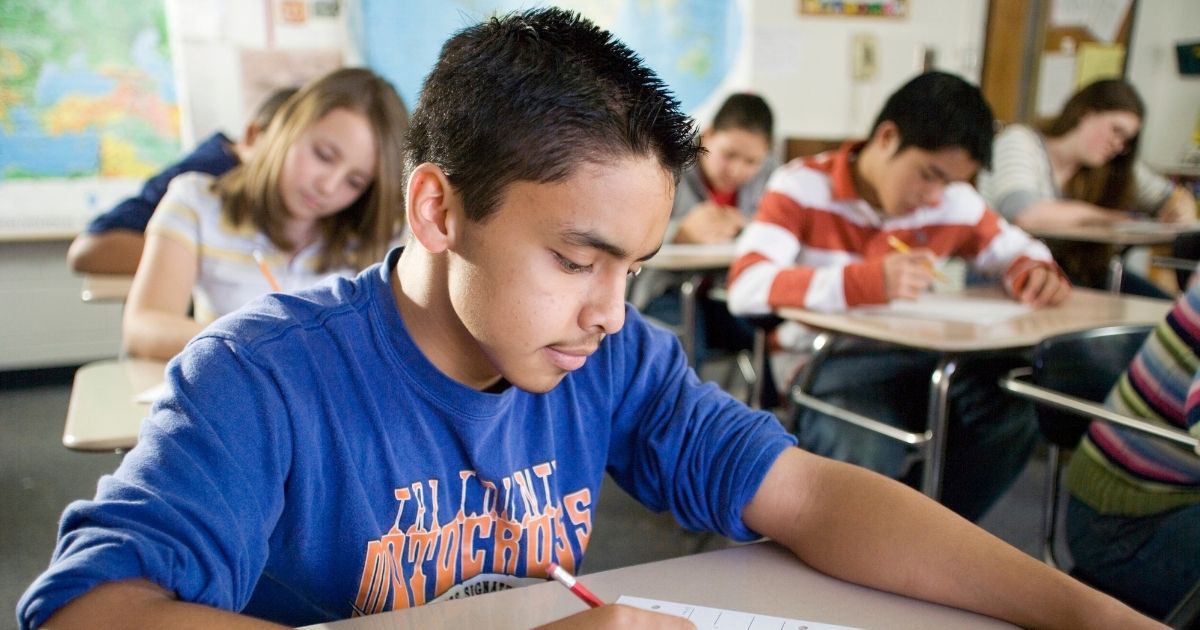 A stock photo shows students in the classroom working at their desks.