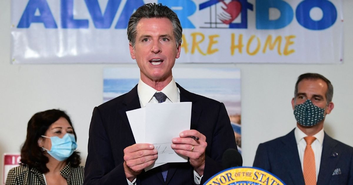 California's Gov. Gavin Newsom displays the seven bills signed as he joins city leaders in celebration of legislation to support the state's expansion of mental health services and behavioral health housing as part of California's package to address the homeless crisis in Los Angeles, California, on Sept. 29.