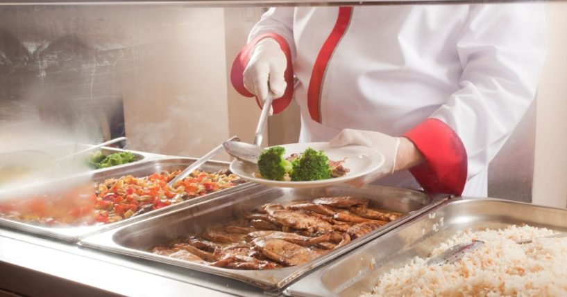 A stock photo shows a chef serving food from behind a lunch service station.