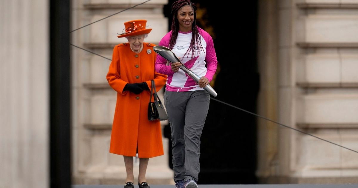 Queen Elizabeth II walks with baton bearer Kadeena Cox at the Birmingham 2022 Commonwealth Games Queen's Baton Relay event outside Buckingham Palace in London on Thursday.