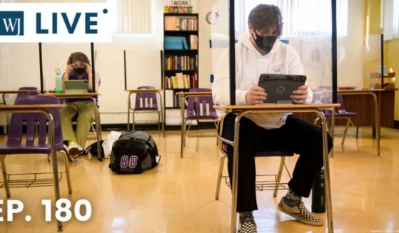 Students sitting behind barriers work on Apple iPad tablets as they return to in-person learning at St. Anthony Catholic High School during the COVID-19 pandemic on March 24 in Long Beach, California.